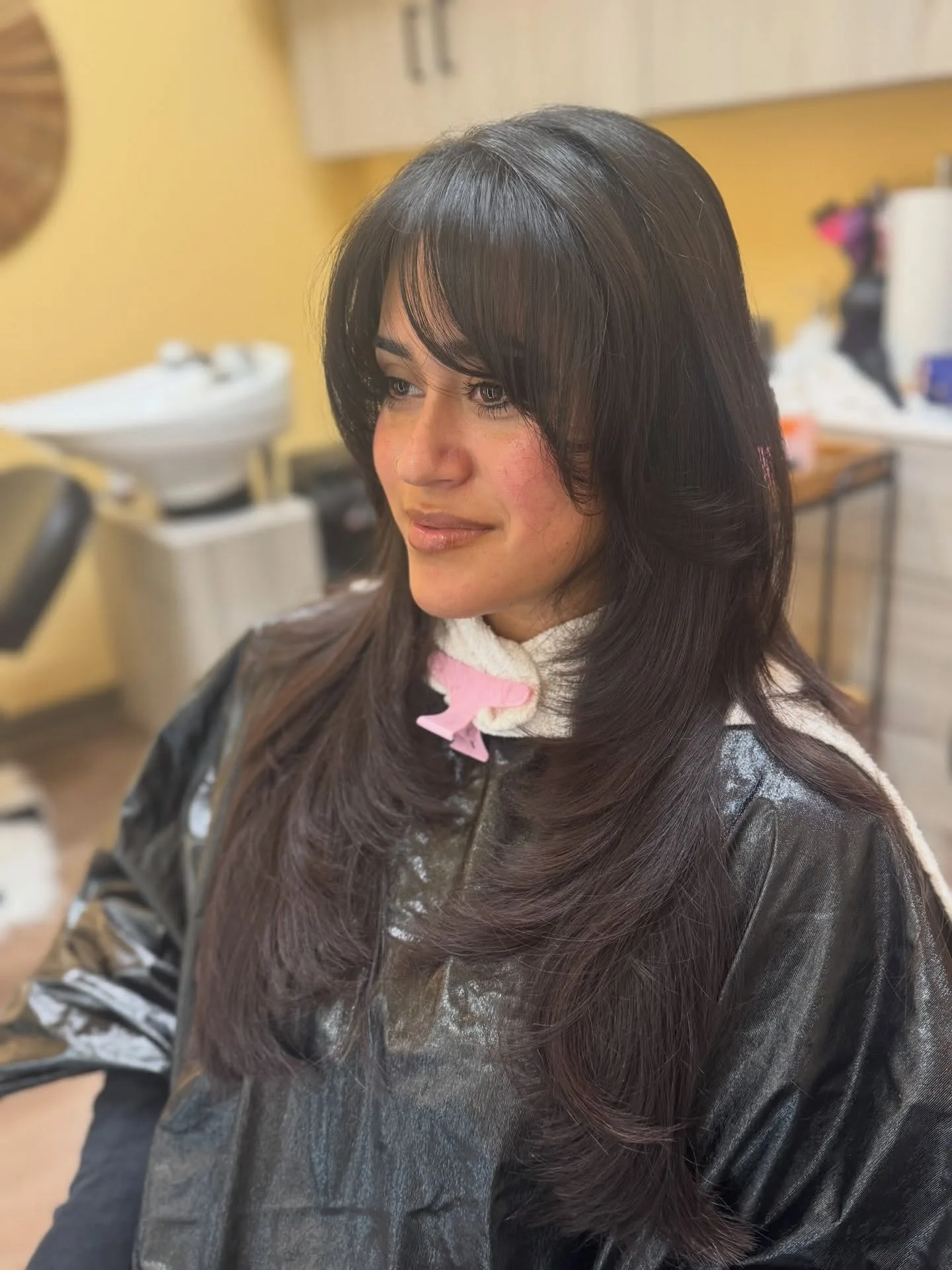 Long dark hair with full fringe and soft face-framing layers.