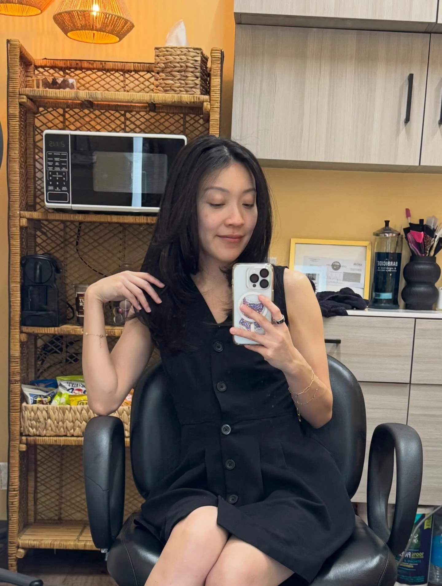 Client taking a salon mirror selfie after a dark layered haircut.
