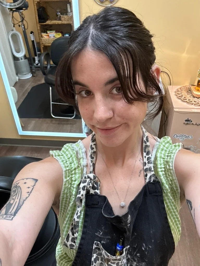 Izzy smiling in her salon while wearing her stylist apron.